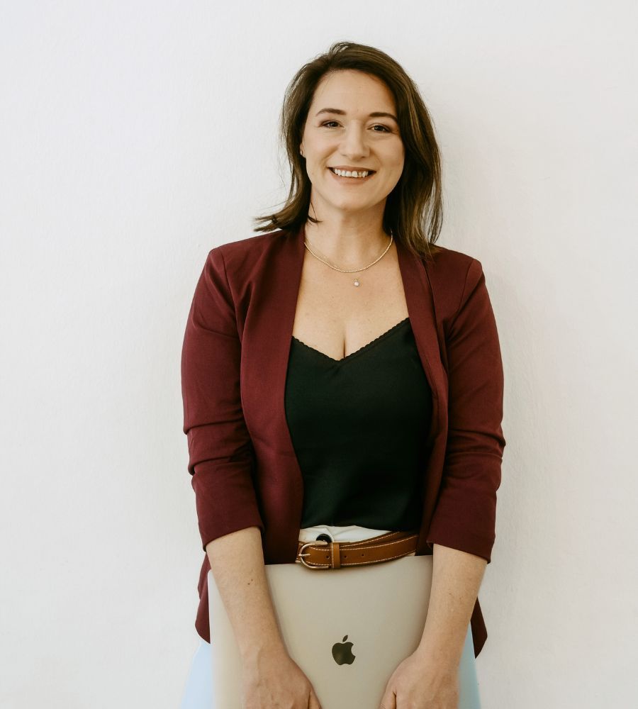 Sarah Kerstin mit lächelt und hält dabei einen Laptop in der Hand.