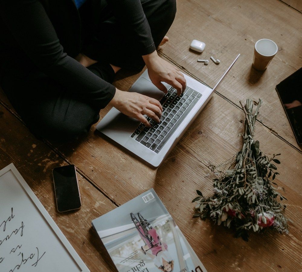 Sarah Breuer vom digitalen Coworking am Laptop. Daneben steht ein Kaffeebecher